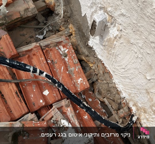 רעפים שבורים על גג עם קיר מתקלף